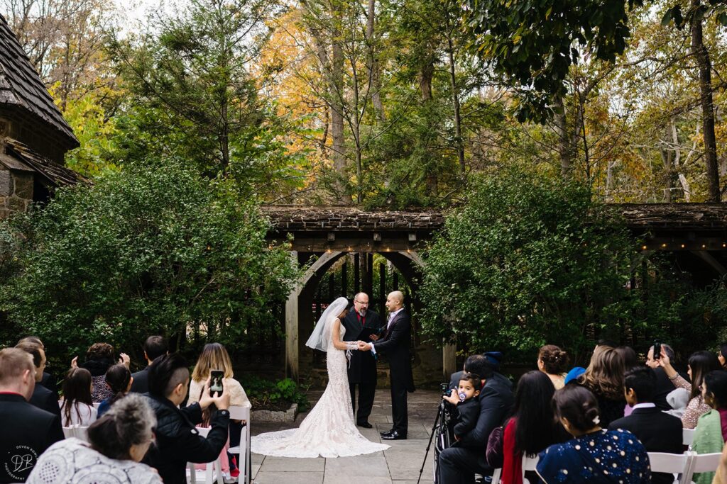 A couple holding hands and standing up during their wedding ceremony 