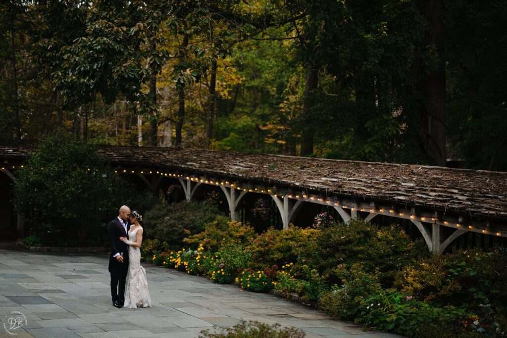 Newlyweds standing close together surrounded by greenery 