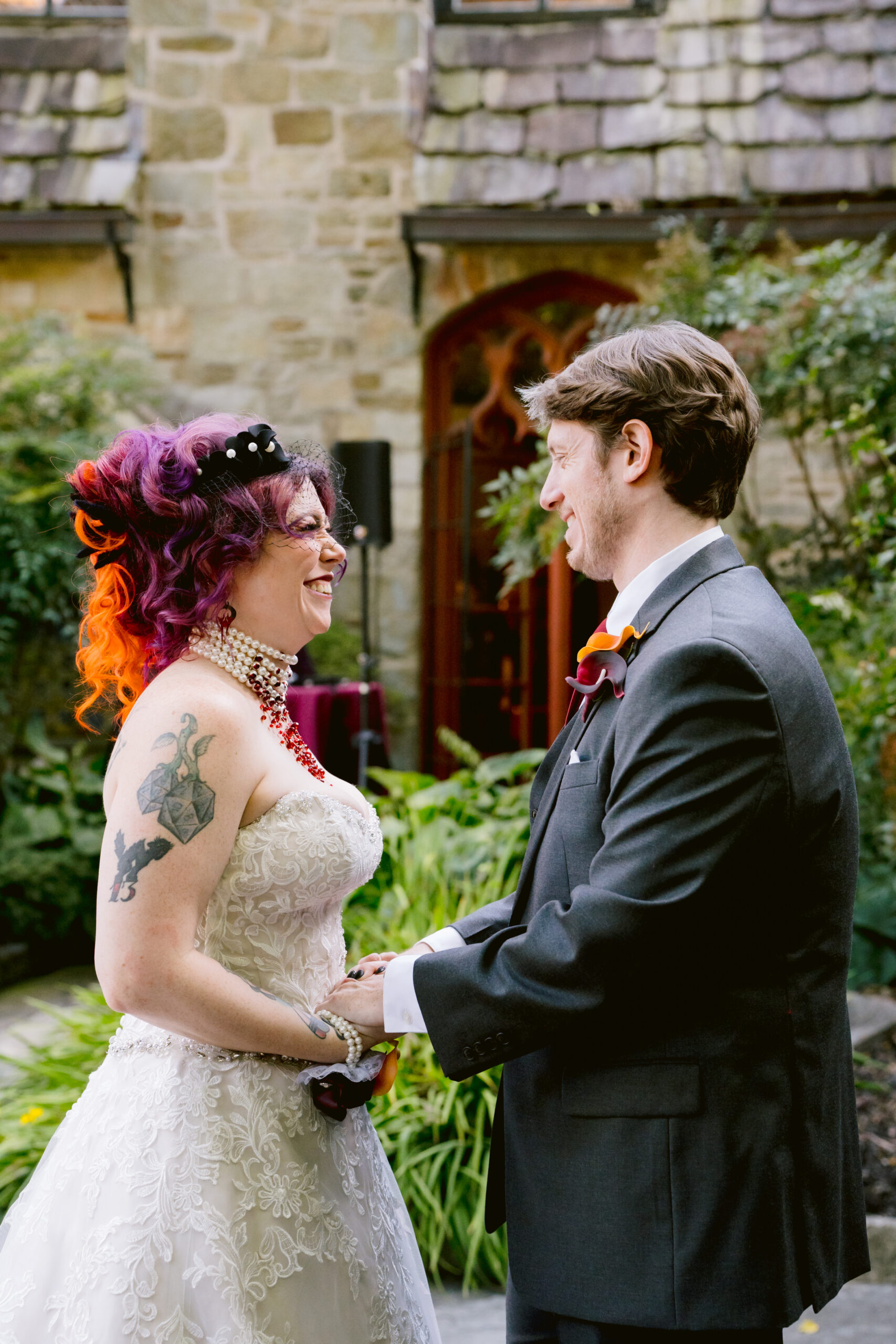 woman in a wedding dress laughing and holding hands and looking at a man in a tuxedo 