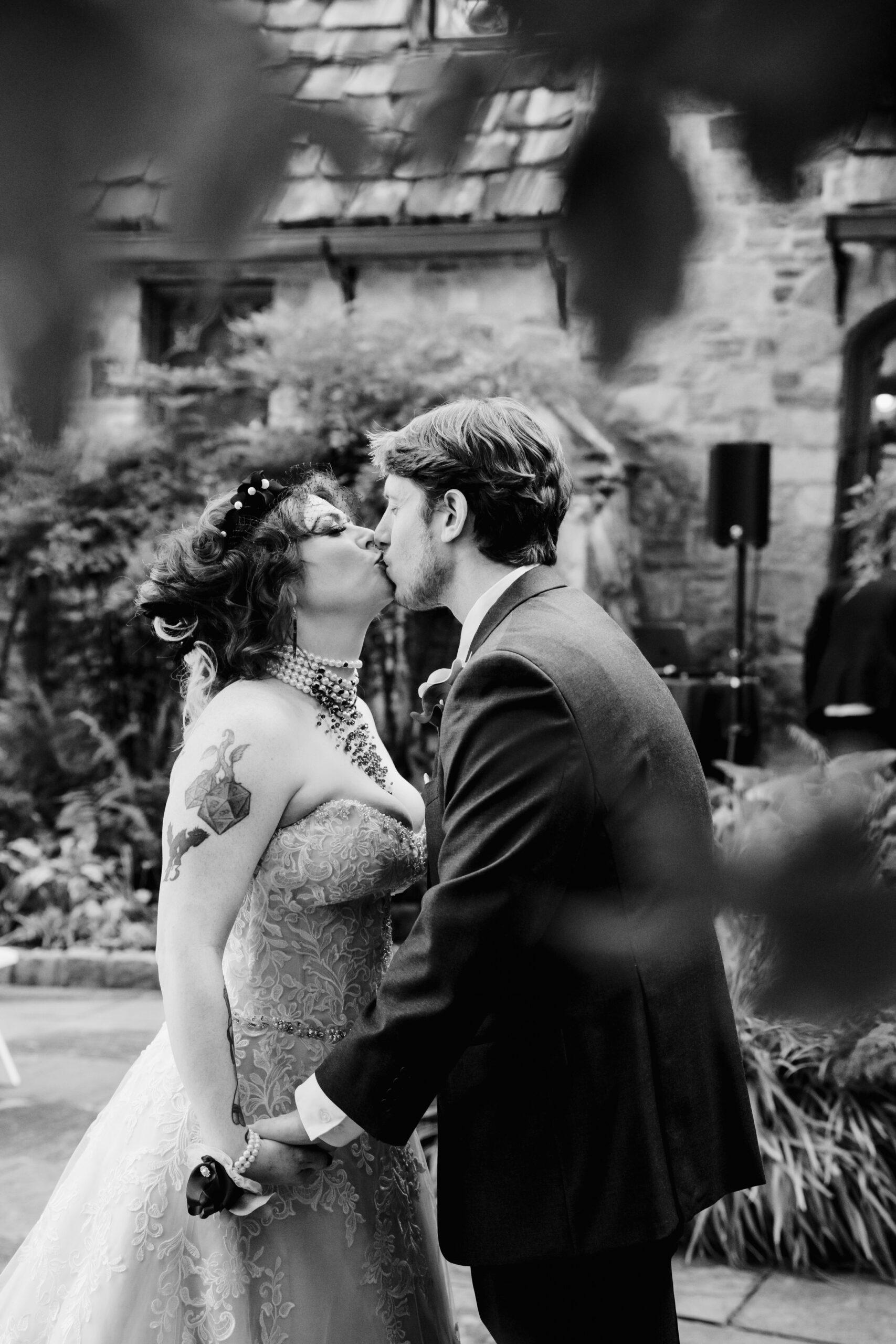 black and white photo of a woman in a wedding dress kissing a man in a tuxedo 