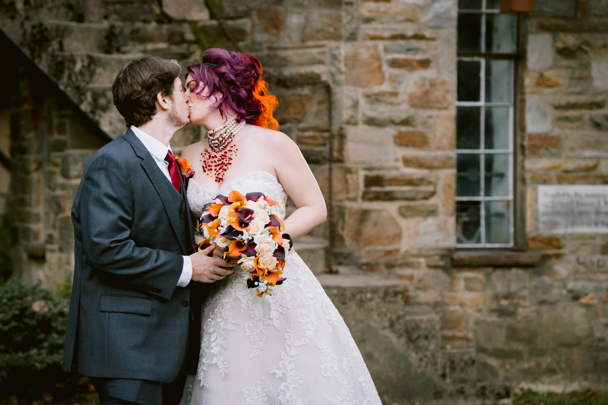 woman in a wedding dress holding a boquet of flowers kissing a man in a tuxedo