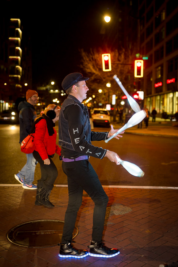 Juggler with three pins being juggled as he crosses the street.