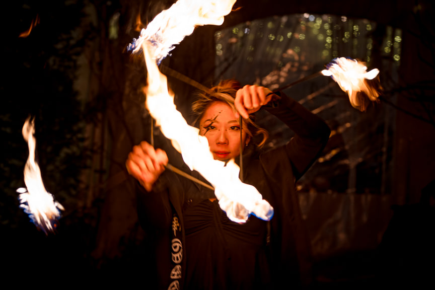 Fire performer looking straight to the camera between flames while spinning fire.