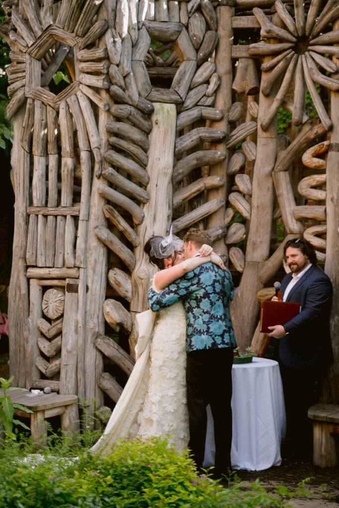 A couple kissing during their first kiss at their outdoor wedding ceremony 