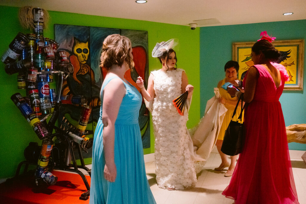 A person in a wedding dress standing in a colorful room with their wedding party 