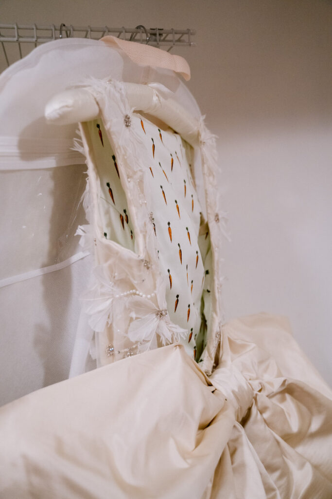 A wedding dress hanging up showing off a patterned lining to it. 