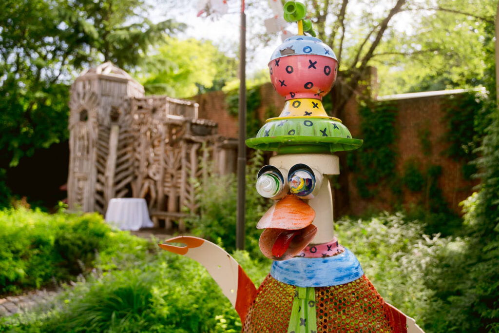 A sculpture in a garden with another wooden sculpture in the distance 