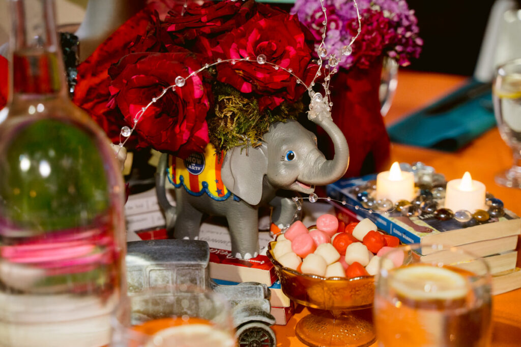 Various trinkets, flowers, candles, and candy sitting on a wedding reception table 