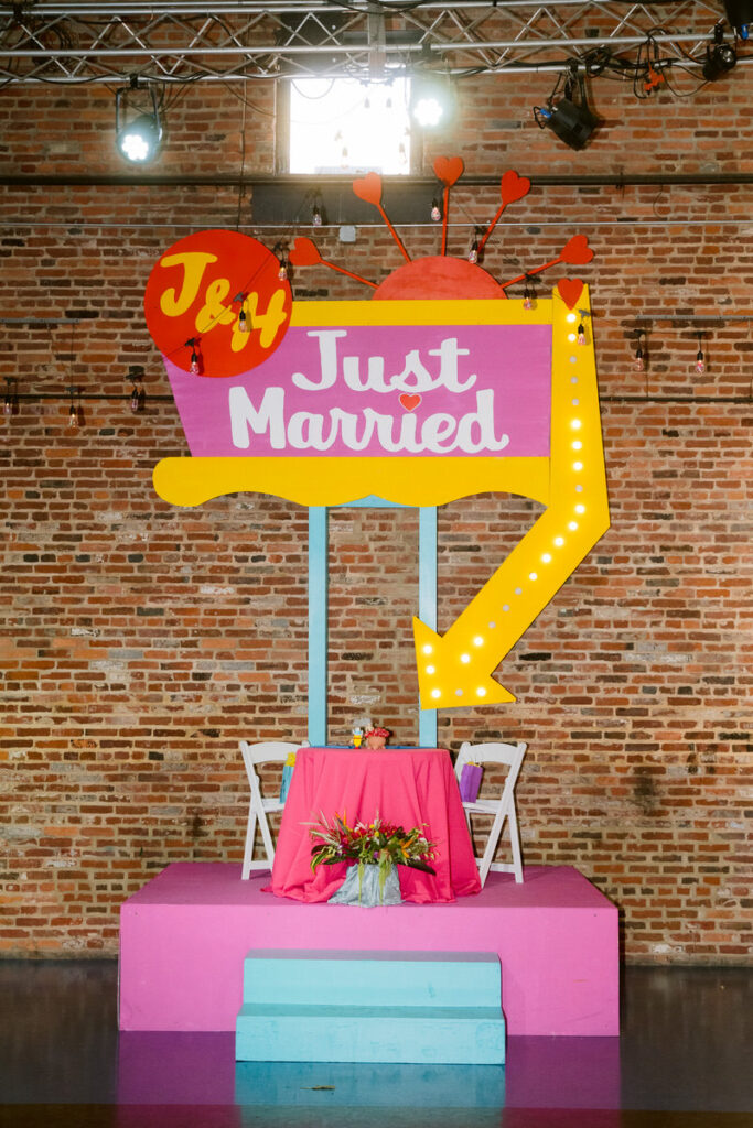 A colorful marquee pointing down towards a small wedding reception table on a platform. 