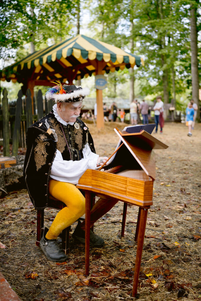 A person in medieval clothes playing a small instrument 