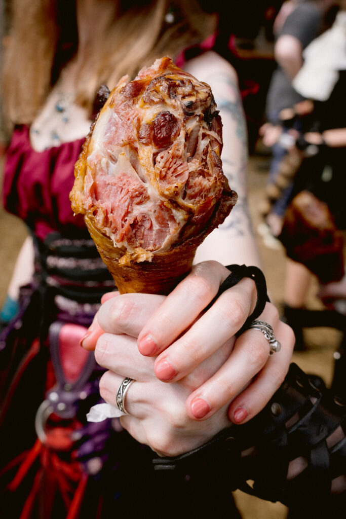 Two hands holding out a turkey leg and showing off wedding rings 
