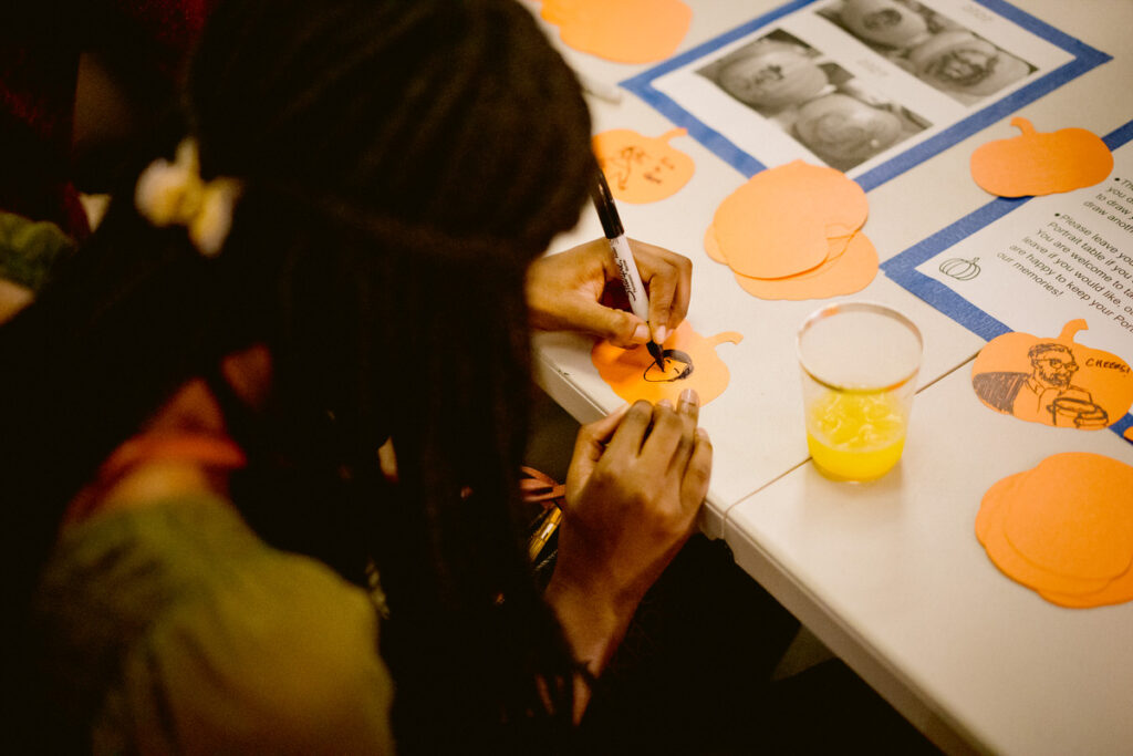 A person drawing a portrait on a pumpkin shaped paper 