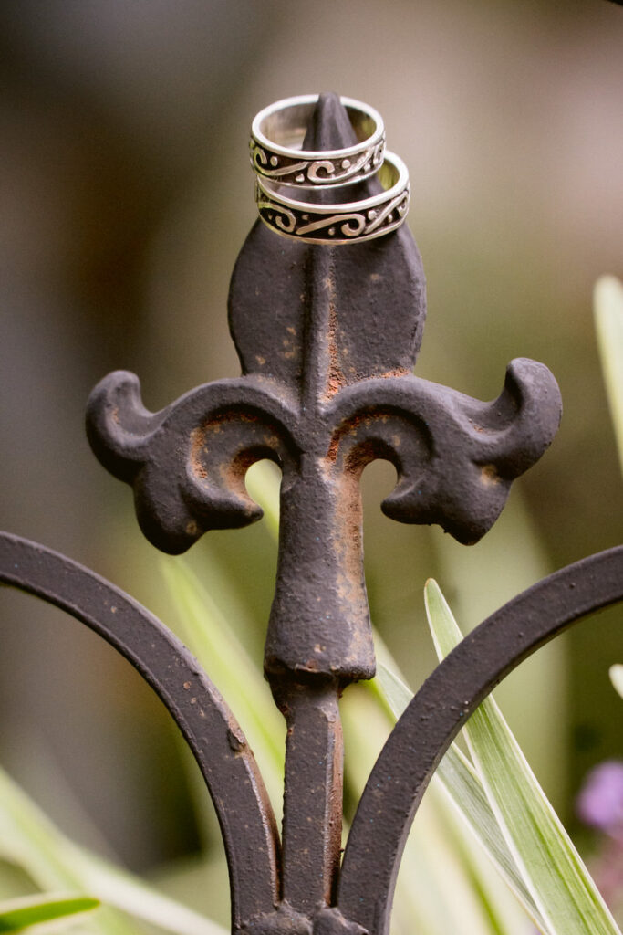 Wedding rings sitting on the tip of a metal fence 