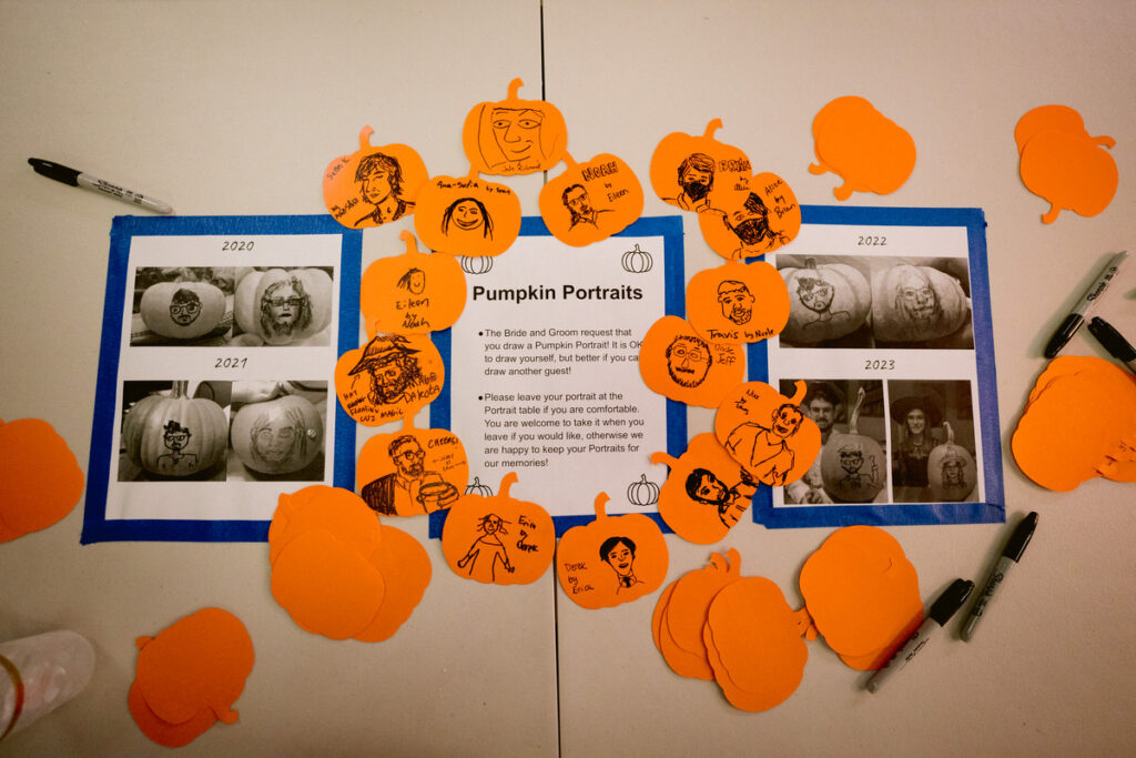 Small portraits drawn on paper pumpkins laid out on a table 
