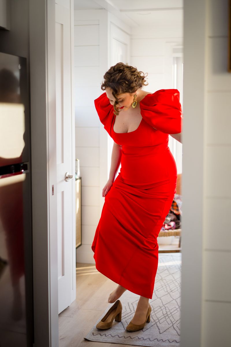 a woman in a red dress putting on her heels 