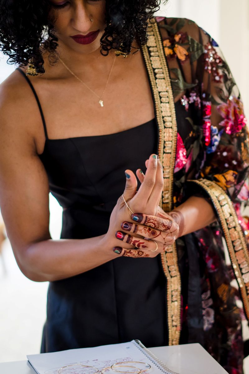 a woman in a black dress and colorful kimono putting on a bracelet 