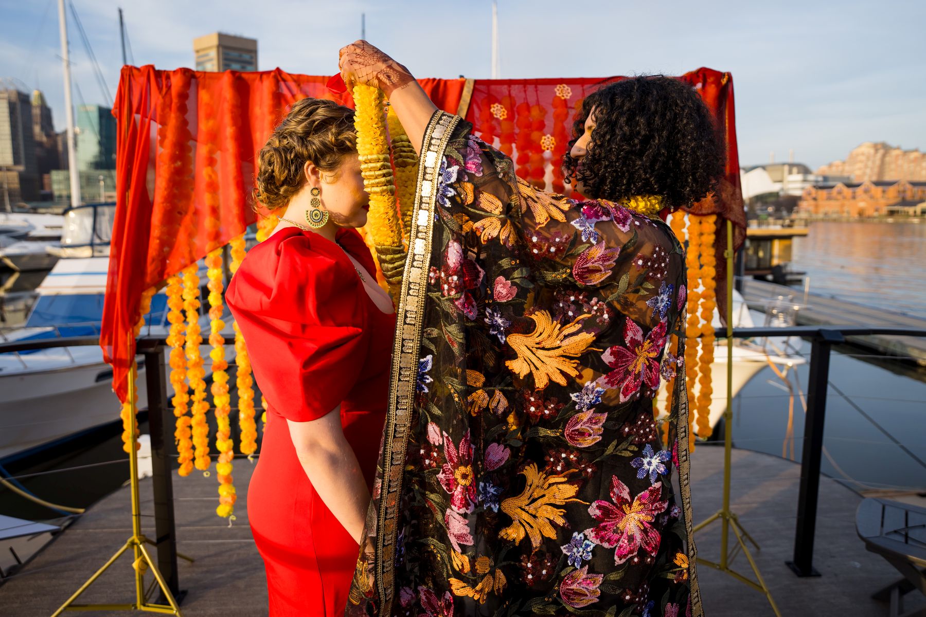 a woman in a colorful kimono is placing a yellow lei over her partner's head 