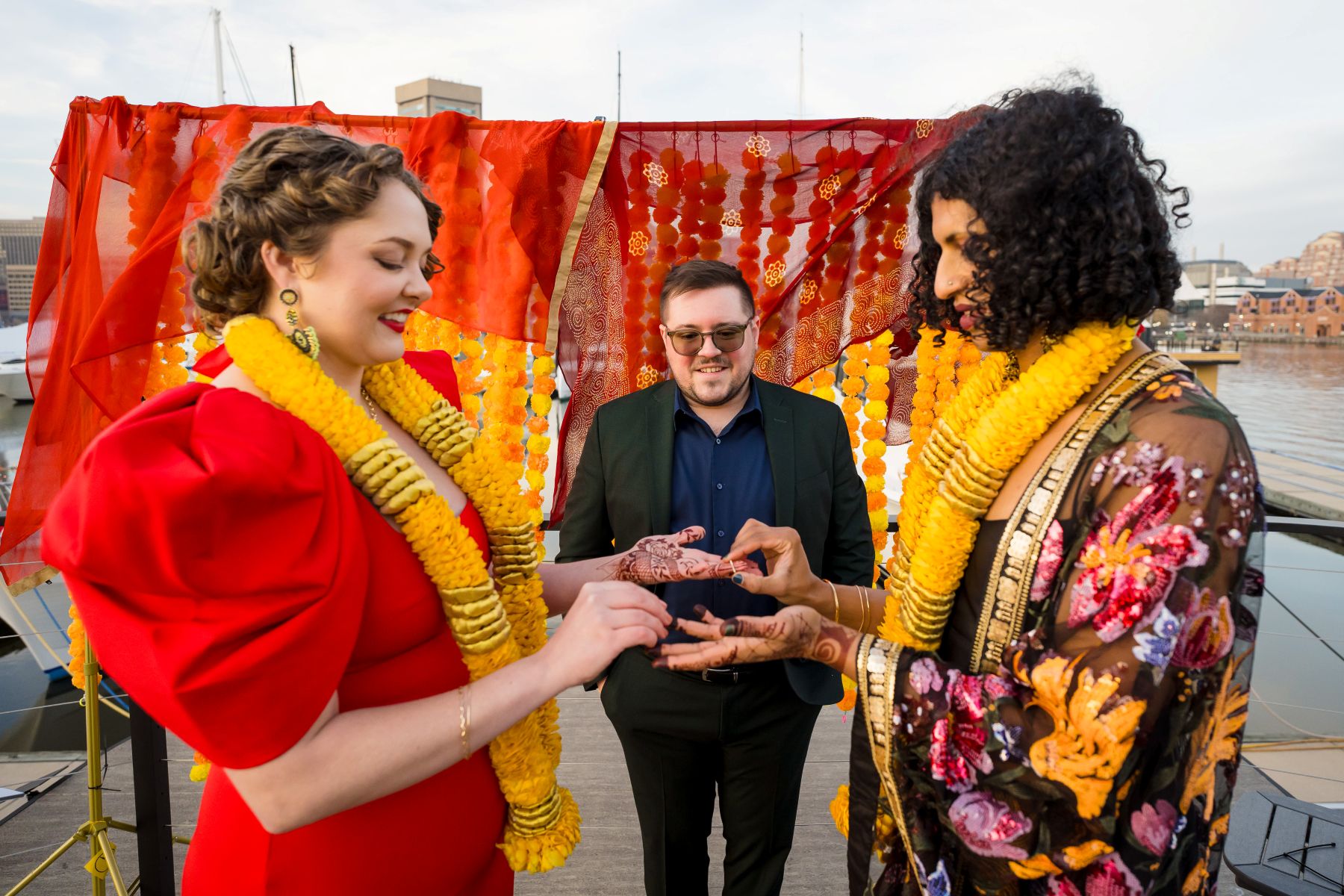 a couple exchanging rings at their wedding ceremony with their officiant standing behind them 