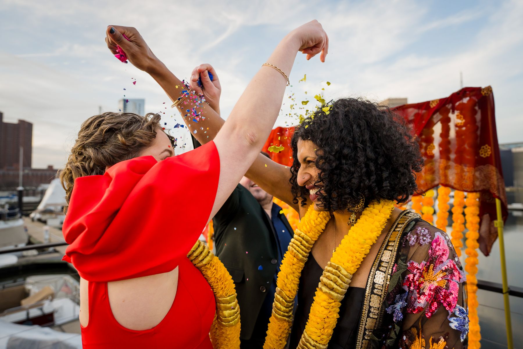 a couple sprinkling confetti in one another's hair and laughing at each other 